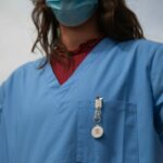 A nurse standing at the ready, wearing scrubs with a MedicAlert ID attached.