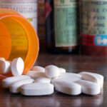 Prescription opioids with many bottles of pills in the background. Concepts of addiction, opioid crisis, overdose and doctor shopping