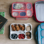 Lunch boxes near notebooks on table