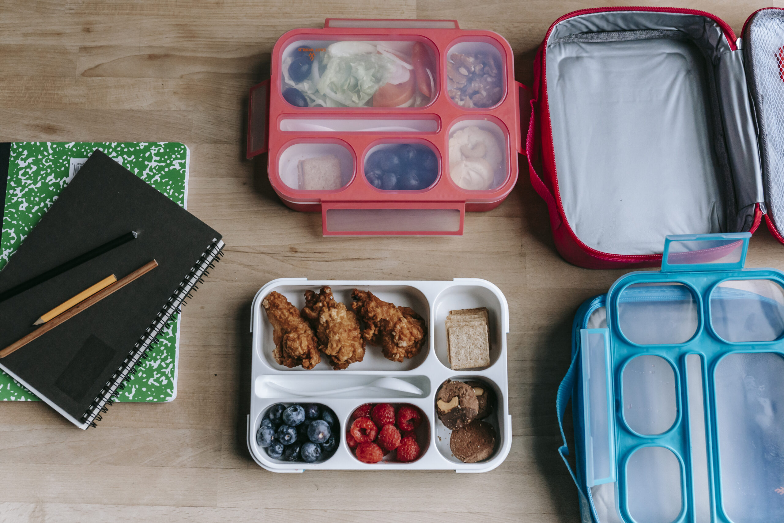 Lunch boxes near notebooks on table