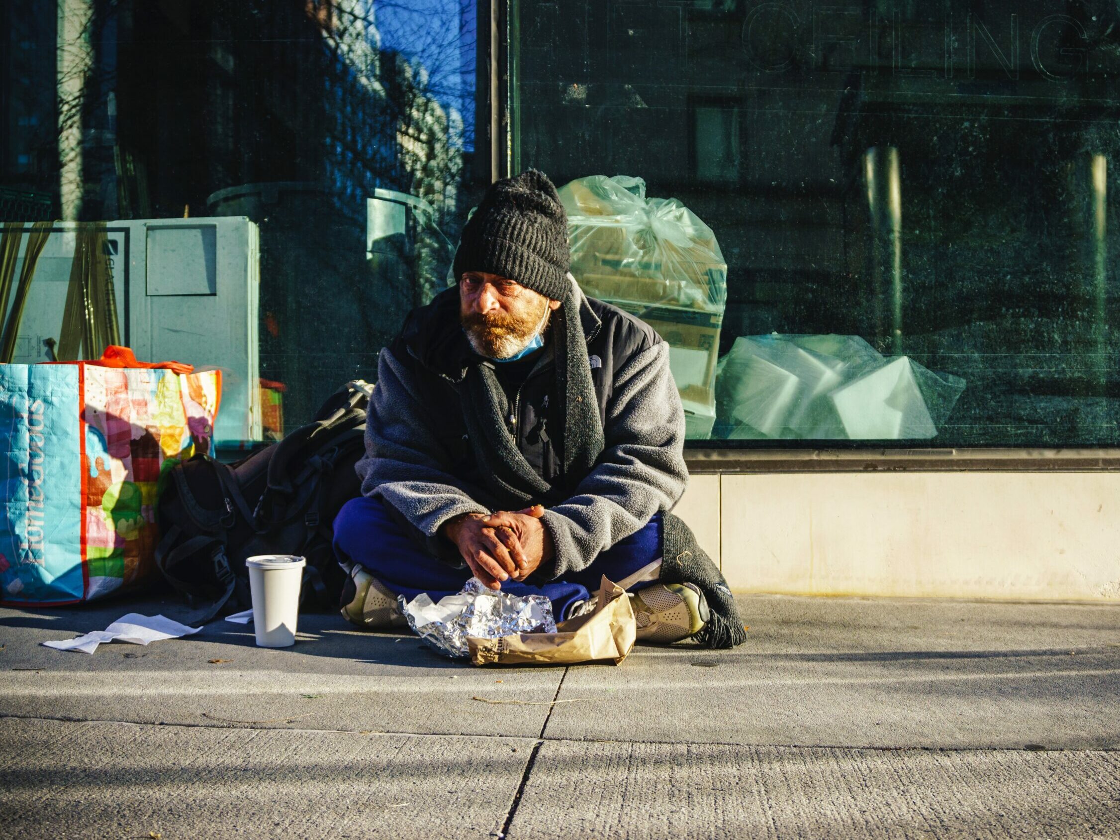 A homeless man eats breakfast on the street on Upper East Side of Manhattan.