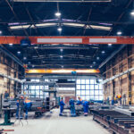 Large factory hall, blue-collar workers at work.
