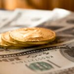 three round gold-colored coins on 100 US dollar banknotes