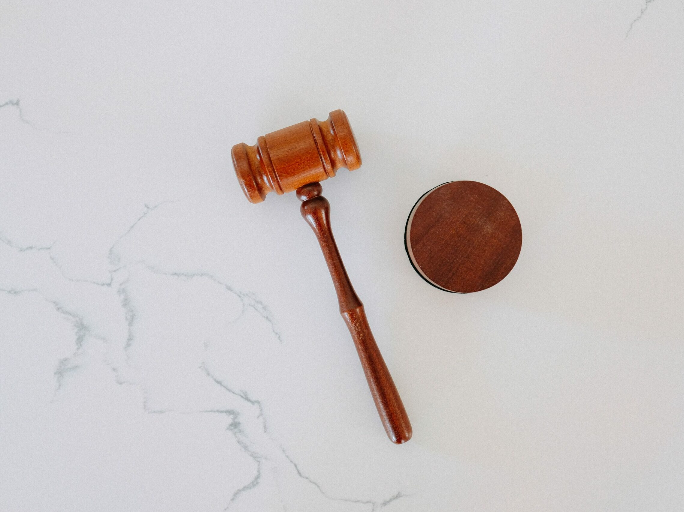 A wooden gavel on a white marble backdrop.