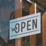 CU we are open sign hanging on the entrance door of a small cafe. Small business concept