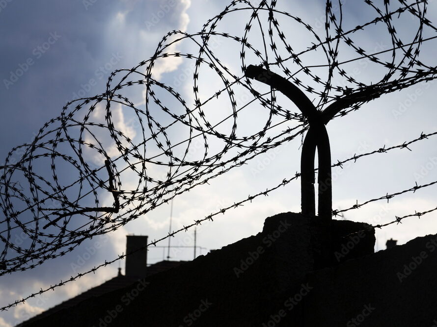Dramatic clouds behind barbed wire fence on a prison wall