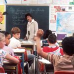 Children in a Classroom. In the back of a classroom, are children about 11 years old with a female teacher talking about the subject - If Someone in Your Family Has Cancer. Photographer Michael Anderson