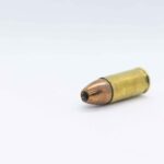 gold and silver bullet on white surface