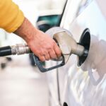 Pumping gas at gas pump. Closeup of man pumping gasoline fuel in car at gas station.