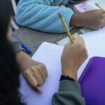 Crop kids doing homework on table