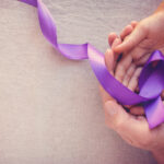 Hands holding Purple ribbons, toning copy space background, Alzheimer disease, Pancreatic cancer, Epilepsy awareness, domestic violence awareness