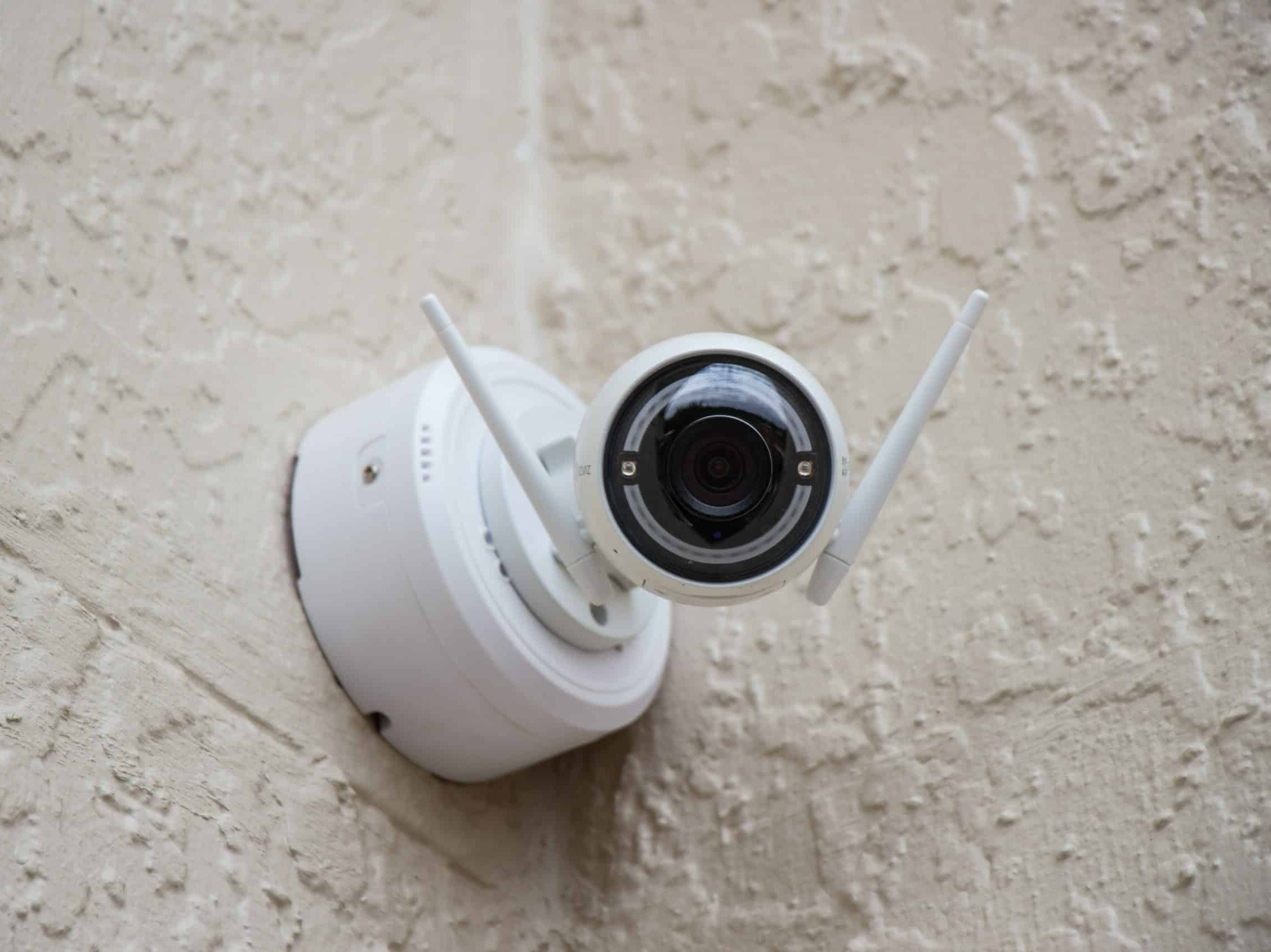 white surveillance camera hanging on wall