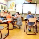 Children sitting on brown chairs inside the classroom