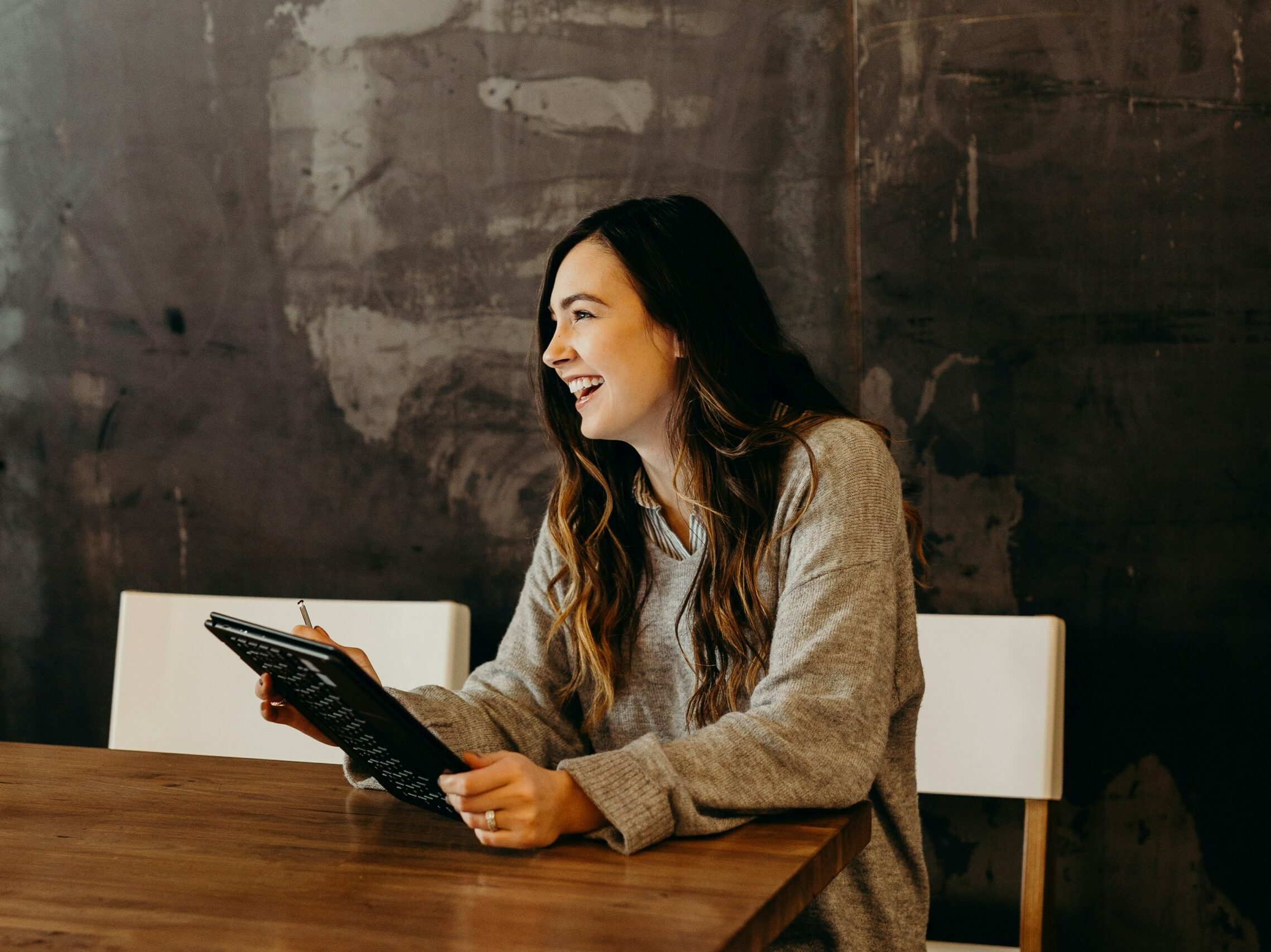 woman sitting around table holding tablet