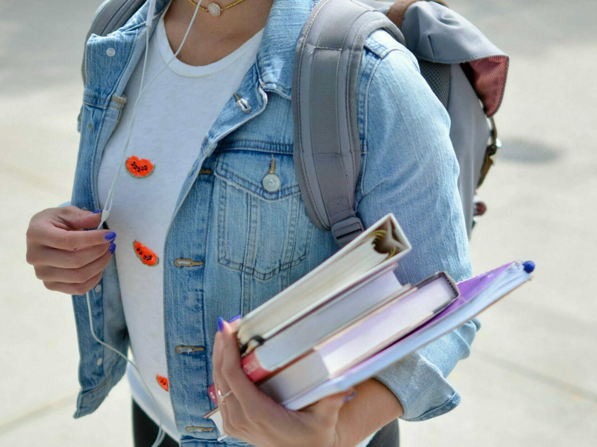 woman wearing blue denim jacket holding book