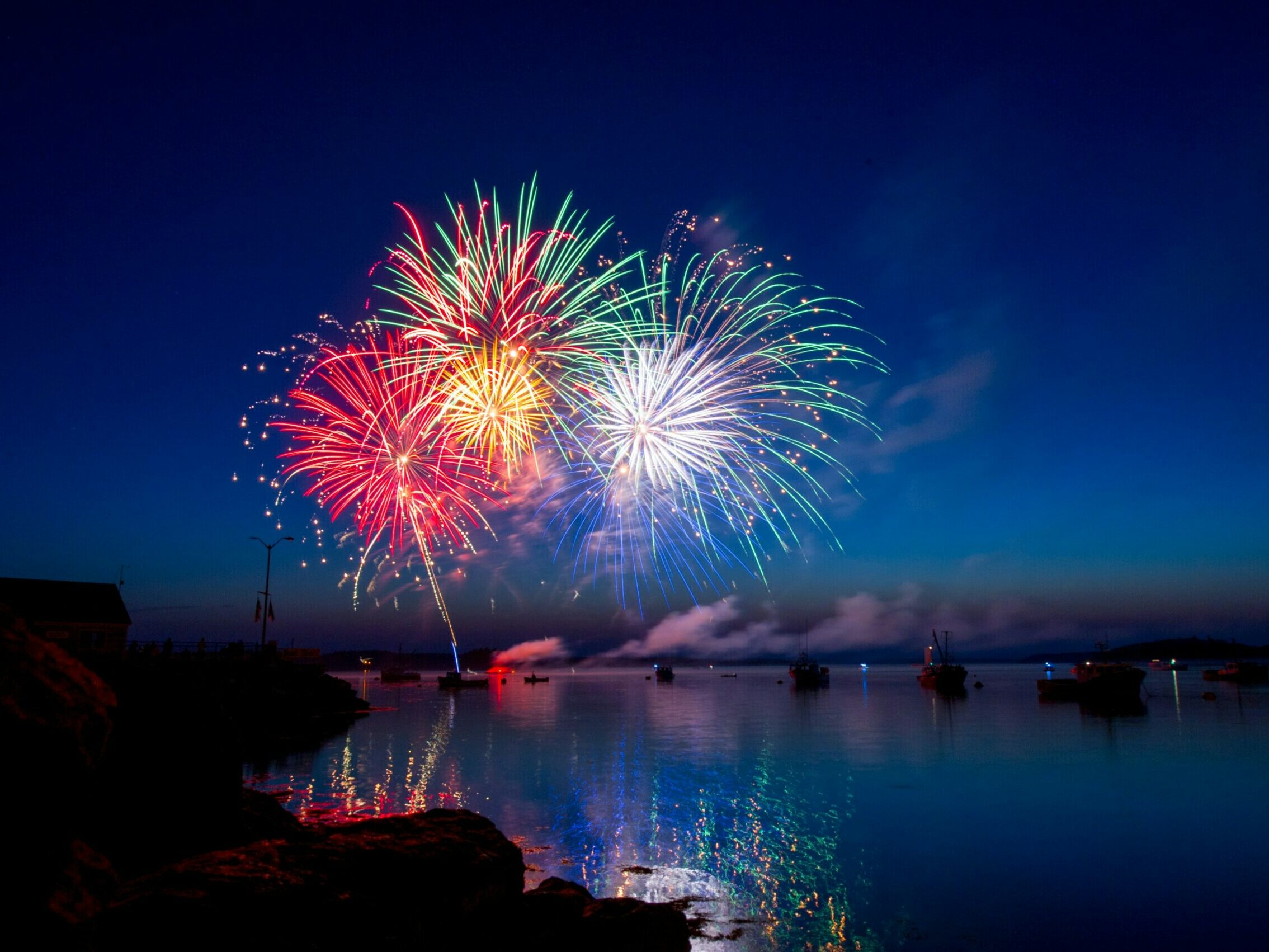 A fireworks display in the harbor of Lubec Maine.  The dusk sky, water and boats provided a beautiful setting for the colorful show.