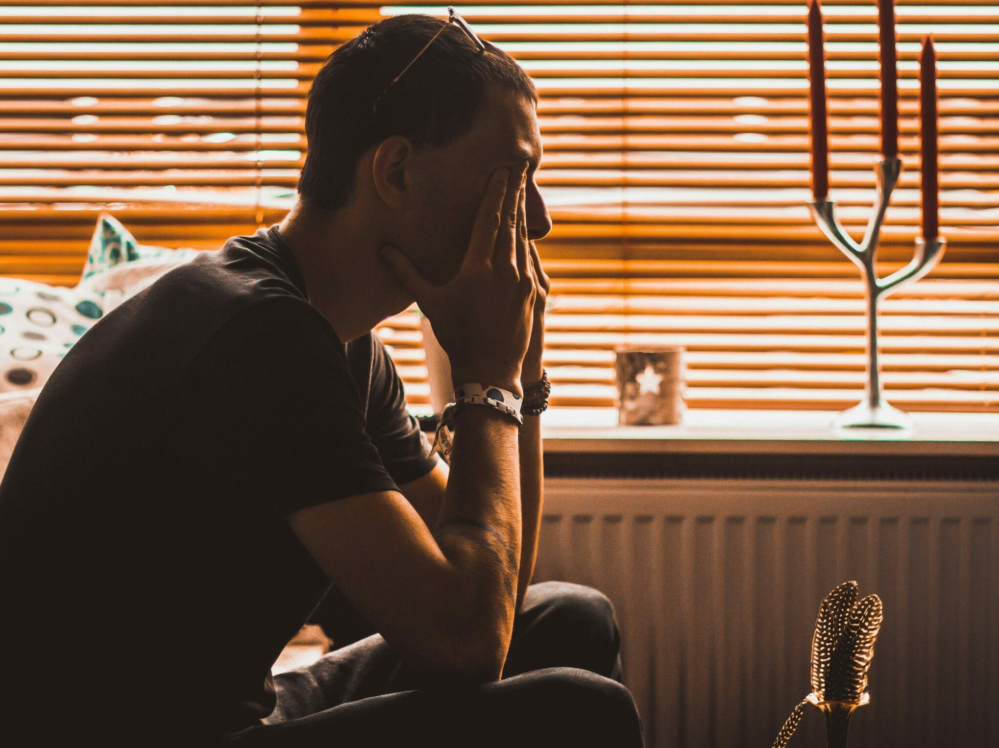 man sitting on chair covering his eyes