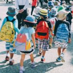 group of people wearing white and orange backpacks walking on gray concrete pavement during daytime