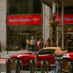 a red sports car is parked in front of a bank of america