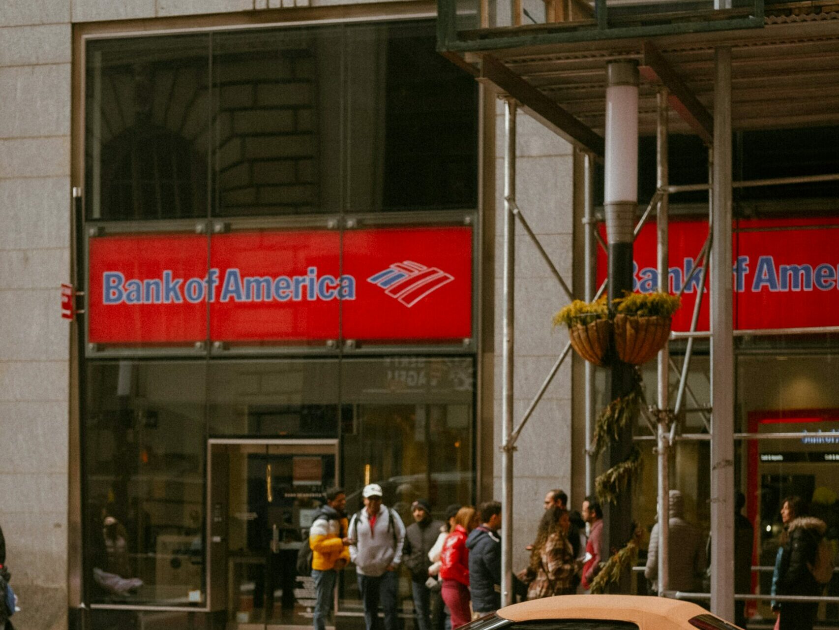 a red sports car is parked in front of a bank of america