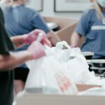 person in blue crew neck t-shirt holding white plastic bag