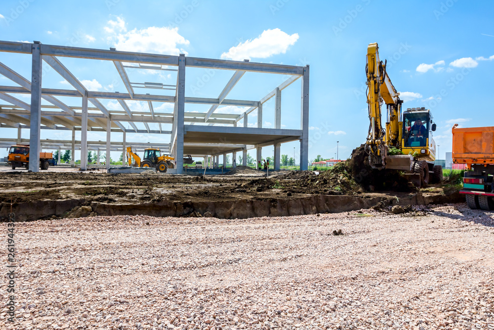 Backhoe is loading a truck with ground on building site